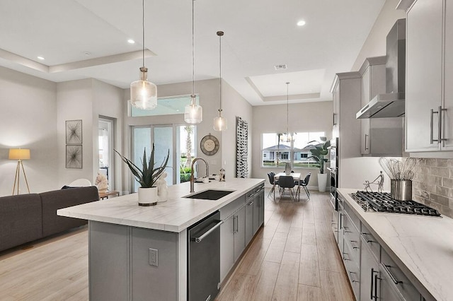 10097 Driftwood Way, Palm Beach Gardens, FL 33412 - kitchen featuring wall chimney range hood, appliances with stainless steel finishes, a sink, a raised ceiling, and gray cabinetry