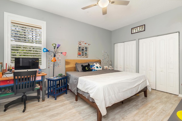 bedroom featuring light wood-type flooring, multiple closets, and a ceiling fan