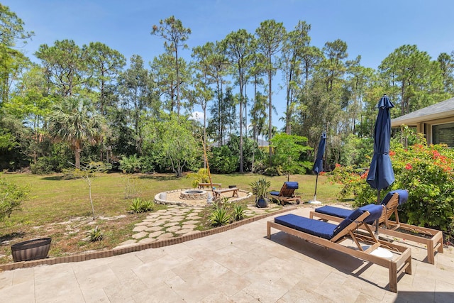 view of patio / terrace with an outdoor fire pit and view of scattered trees