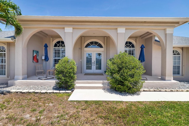 doorway to property featuring french doors, stucco siding, and covered porch