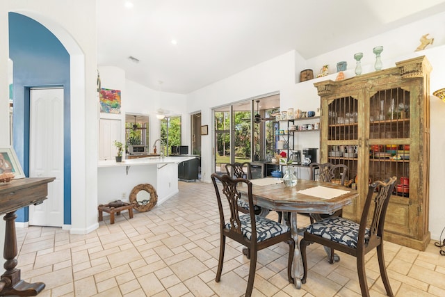 dining space with vaulted ceiling, baseboards, and arched walkways