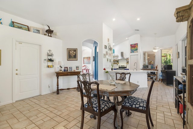 dining space featuring arched walkways, a ceiling fan, recessed lighting, baseboards, and high vaulted ceiling