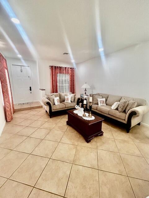 living room with light tile patterned floors, visible vents, and baseboards