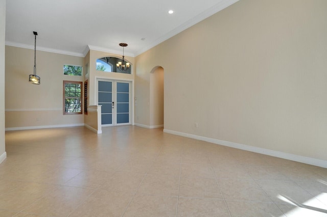 empty room with baseboards, ornamental molding, an inviting chandelier, light tile patterned flooring, and arched walkways