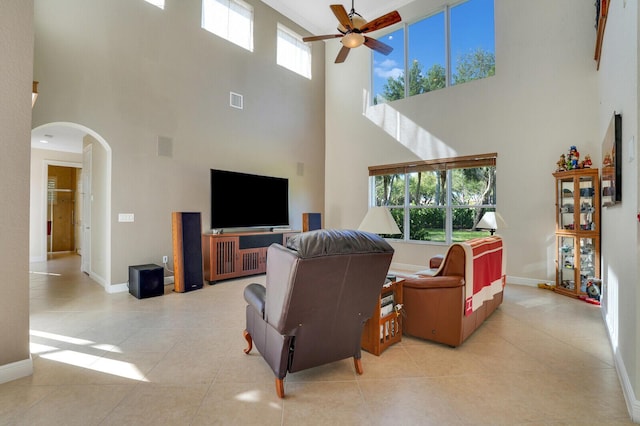 living area featuring arched walkways, light tile patterned floors, baseboards, and ceiling fan