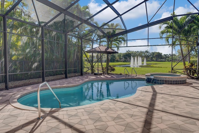 view of pool featuring a yard, glass enclosure, a pool with connected hot tub, and a patio