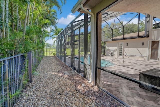 pool with glass enclosure, a patio, and fence