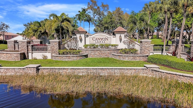 community sign featuring a yard and a water view