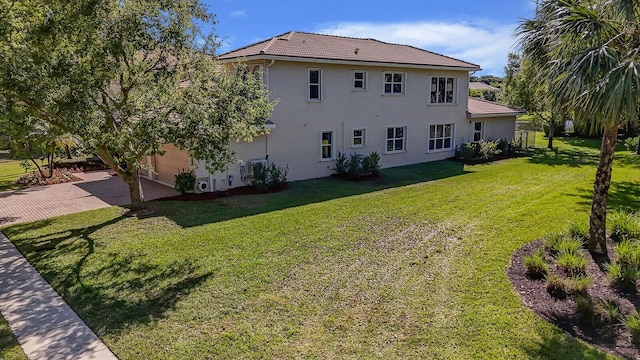 view of home's exterior with stucco siding, driveway, a tile roof, and a yard