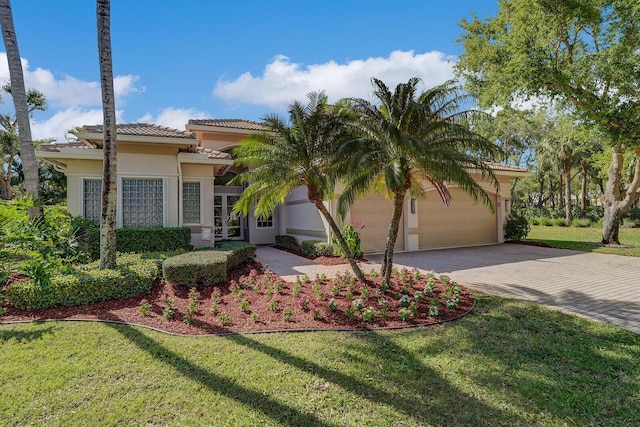 view of front of home featuring stucco siding, a tile roof, decorative driveway, an attached garage, and a front yard