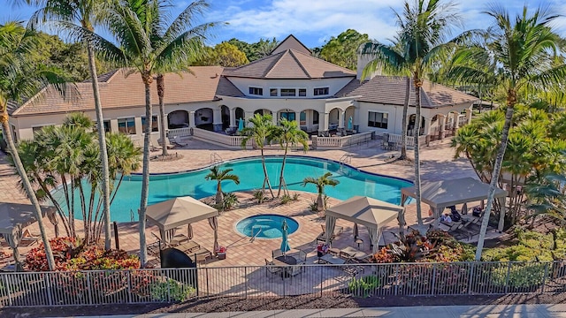 pool featuring a patio area, fence, and a hot tub