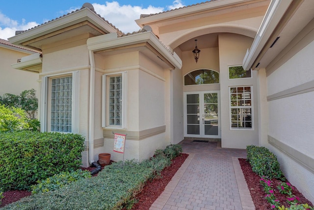 view of exterior entry featuring french doors and stucco siding