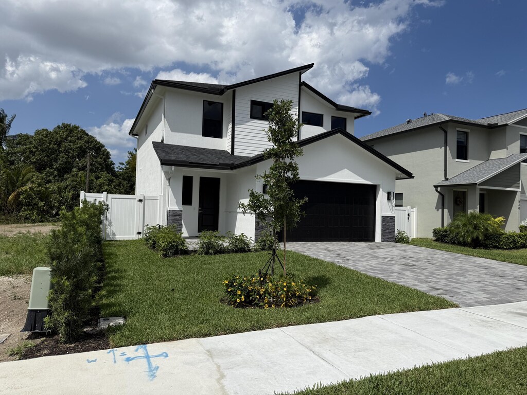 view of front facade with decorative driveway, a front yard, a gate, and a garage