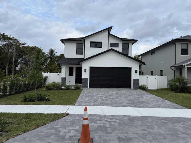 view of front facade with decorative driveway, a front yard, a gate, and a garage