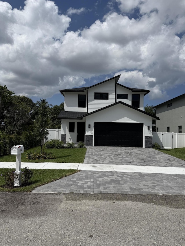 580 Lucky Ln, Delray Beach, FL 33444 - contemporary house featuring decorative driveway, a gate, stone siding, and an attached garage