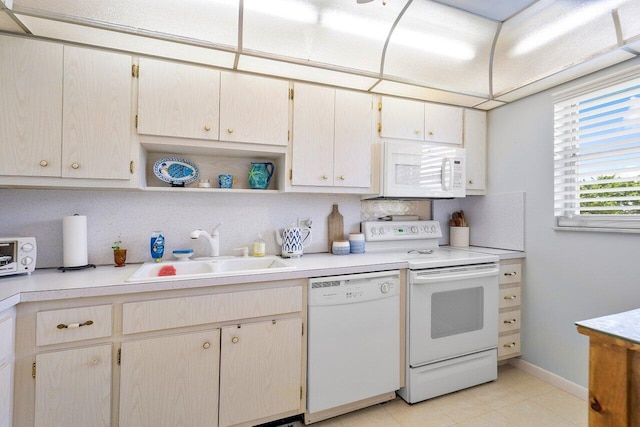 kitchen featuring tasteful backsplash, white appliances, light countertops, and a sink