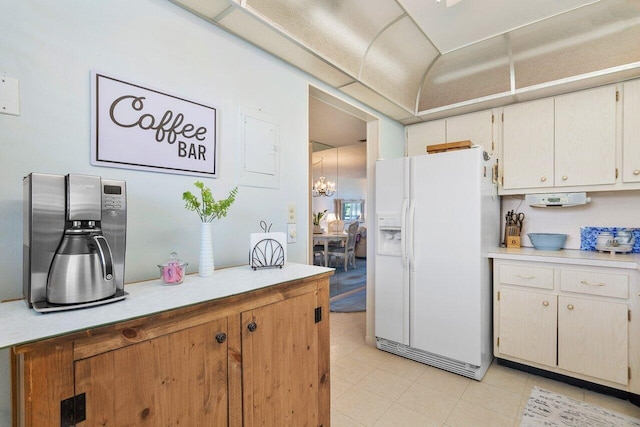 kitchen featuring light tile patterned floors, white refrigerator with ice dispenser, a chandelier, and light countertops