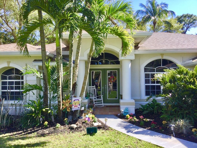 property entrance featuring stucco siding and roof with shingles