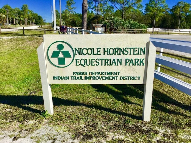 community / neighborhood sign with fence and a lawn