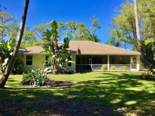 exterior space featuring stucco siding, a shingled roof, a front yard, and a sunroom