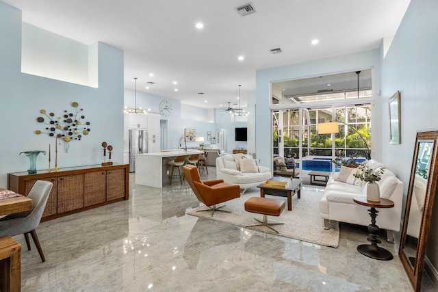 living area featuring recessed lighting, visible vents, marble finish floor, and a towering ceiling