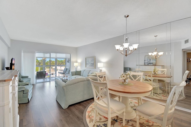 dining room with wood finished floors, visible vents, and a chandelier