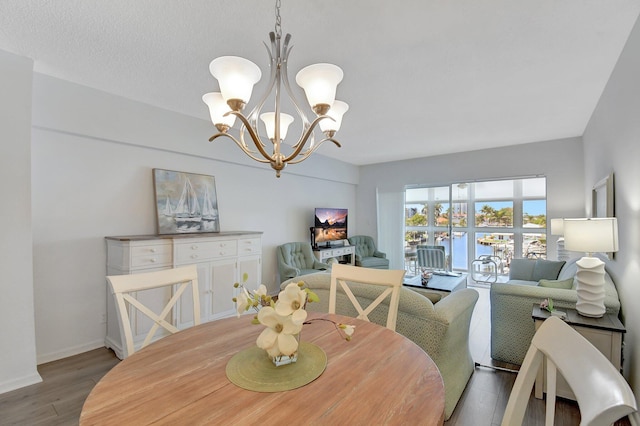 dining area with baseboards, an inviting chandelier, and wood finished floors