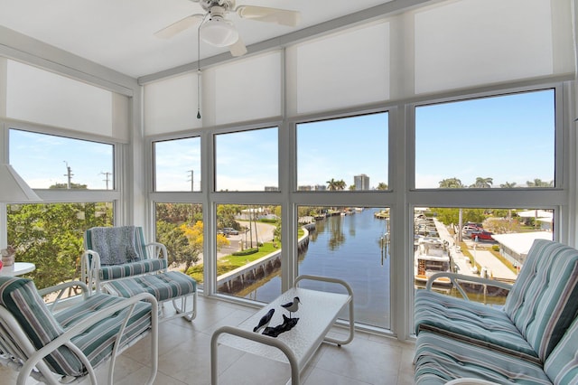 sunroom featuring a ceiling fan and a water view