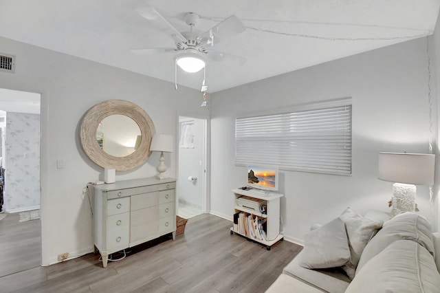 interior space featuring ceiling fan, visible vents, baseboards, and wood finished floors