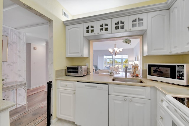 kitchen featuring visible vents, a notable chandelier, a sink, white appliances, and glass insert cabinets