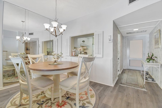 dining room with a chandelier, visible vents, baseboards, and wood finished floors