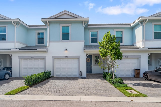 multi unit property featuring a garage, driveway, and stucco siding