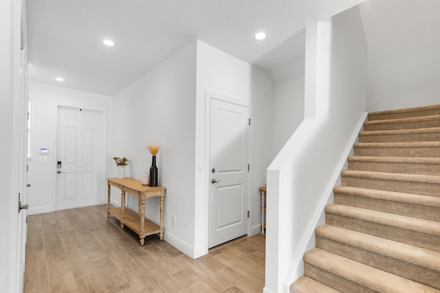 entryway with stairs, recessed lighting, light wood-type flooring, and baseboards