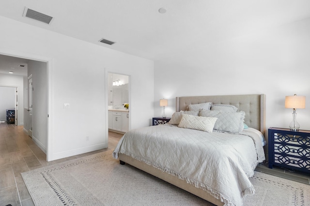 bedroom featuring ensuite bath, baseboards, and visible vents