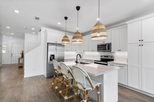 kitchen featuring visible vents, a sink, appliances with stainless steel finishes, light wood-style floors, and a kitchen island with sink