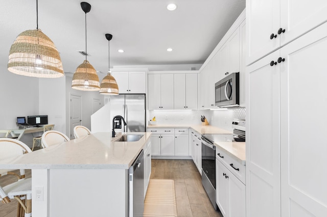 kitchen featuring visible vents, a breakfast bar, a sink, tasteful backsplash, and appliances with stainless steel finishes