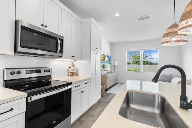 kitchen with visible vents, a sink, appliances with stainless steel finishes, light countertops, and decorative backsplash