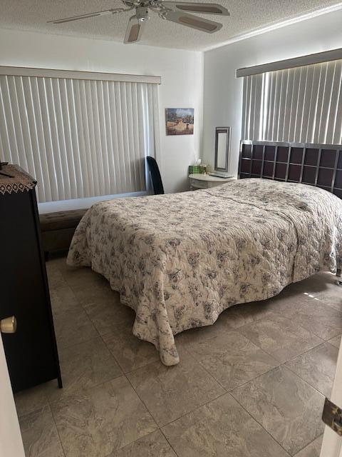 bedroom with a ceiling fan and a textured ceiling