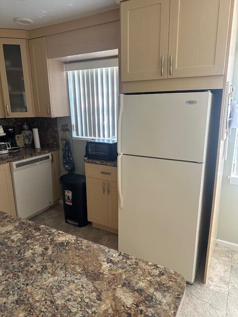 kitchen with dark stone countertops, white appliances, and glass insert cabinets