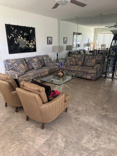 living area with a textured ceiling and a ceiling fan