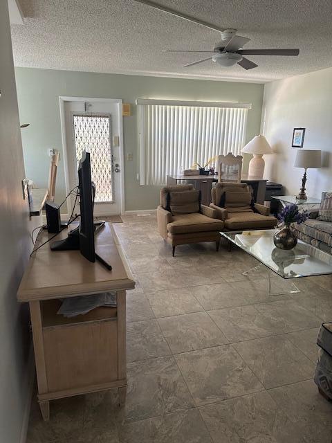 living area featuring baseboards, a textured ceiling, and a ceiling fan