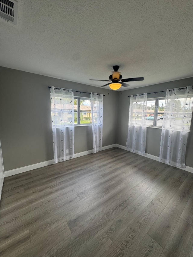 empty room featuring visible vents, baseboards, and wood finished floors