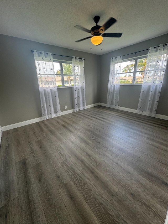 unfurnished room with baseboards, a textured ceiling, wood finished floors, and a ceiling fan