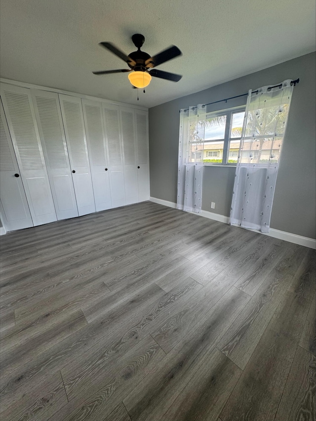 unfurnished bedroom featuring ceiling fan, wood finished floors, baseboards, and a textured ceiling