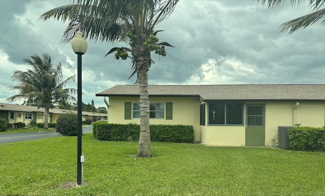 ranch-style home featuring stucco siding, central air condition unit, and a front lawn