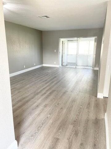 spare room featuring visible vents, baseboards, and wood finished floors