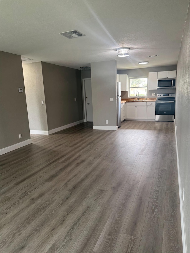 kitchen featuring visible vents, open floor plan, white cabinets, stainless steel appliances, and a sink