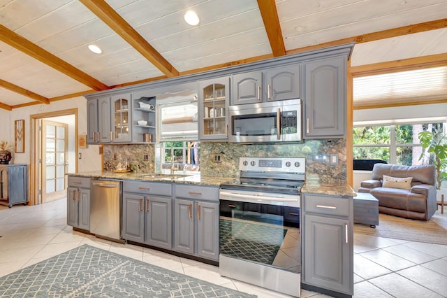 kitchen with decorative backsplash, beam ceiling, appliances with stainless steel finishes, and gray cabinetry