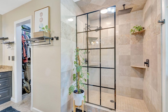 bathroom featuring tiled shower, vanity, and a spacious closet