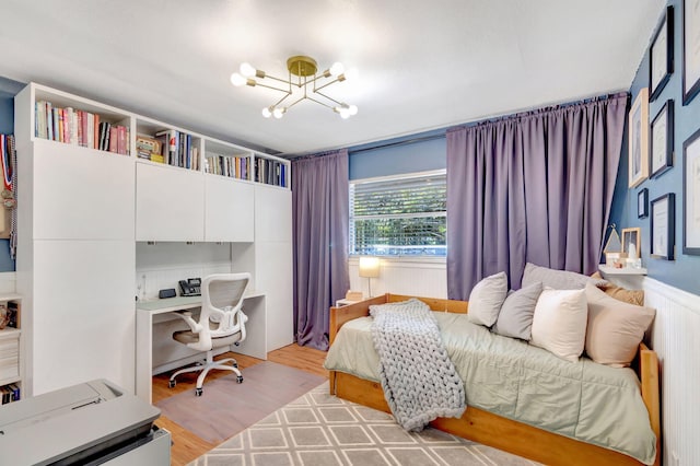 bedroom featuring light wood-style flooring and an inviting chandelier